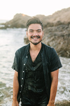 smiling man soaking wet standing on a shore 
