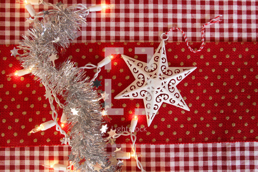 silver tinsel and garland and red fabric with Christmas lights 