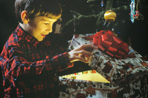 a little boy opening a Christmas gift 