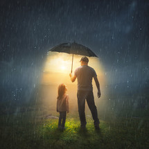 A father holds up an umbrella to protect his child from the rain.