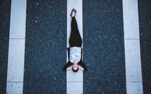 A woman lying on white lines in a parking lot. 