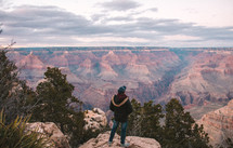 a man standing at the edge of a cliff taking in the view of canyons 