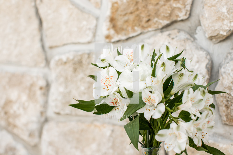 vase of flowers against a stone wall background 