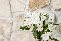 vase of flowers against a stone wall background 