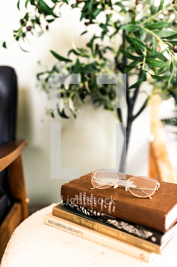 reading glasses on books on an end table 