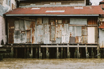 Tin walls of a shed on stilts above a river in Thailand. 