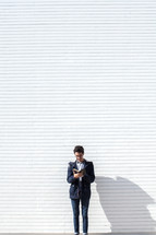 a man standing in front of a white wall reading a Bible 