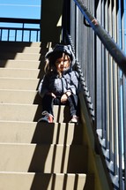 a toddler girl sitting on steps waiting 