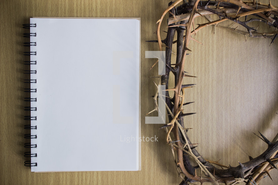 blank notepad and crown of thorns on a wood background 