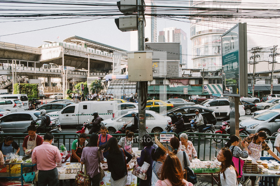 People gathered by vender tables on a street market in Thailand. 