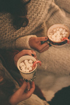 women holding mugs of hot cocoa 