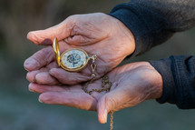 elderly hands holding a pocket watch 