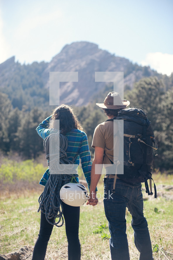 a couple holding hands outdoors while backpacking 
