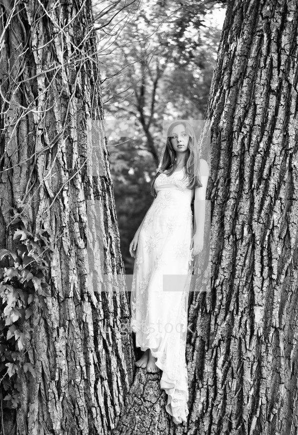 A woman in a white dress standing in a tree