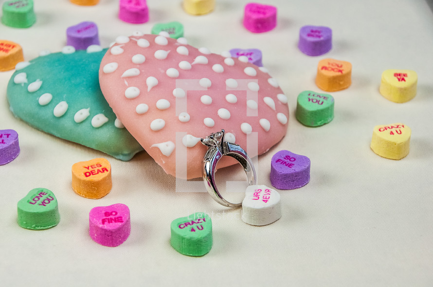 A diamond engagement ring among Valentines cookies and candies.