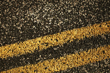 A closeup of a double yellow dividing line painted on a road.