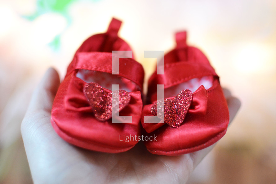 woman holding tiny red baby shoes 