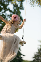 A young girl in a white dress swinging