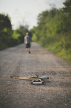 Man walking away from crutches on dirt road.