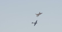 A Black Spitfire plane and an F-16 fighter jet flying together during an airshow