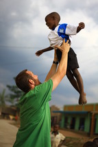 man holding boy in the air making a cross