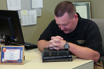 police officer in prayer over a Bible