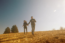 man and woman running down a hill holding hands