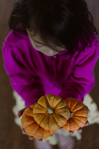 girl holding small pumpkins 