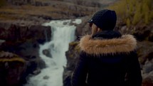 a woman looking out at a waterfall 