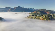 Aerial panoramic view above foggy landscape in autumn. Slow motion time-lapse flight

