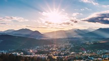 Sunset sky over small European city landscape with sunlight, sunbeam and clouds in beautiful evening Time-lapse
