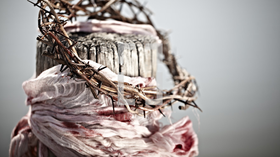 A crown of thorns and a blood-soaked garment hang from a wooden beam.