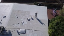 Aerial of a man applying a roof coating on a home