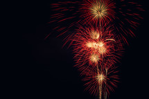 Red and gold fireworks exploding  in a night sky.