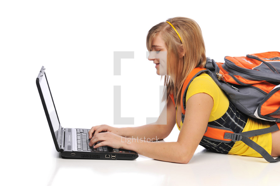 teen girl student with a book bag on a laptop 