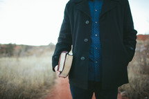 man holding a Bible and journal at his side 