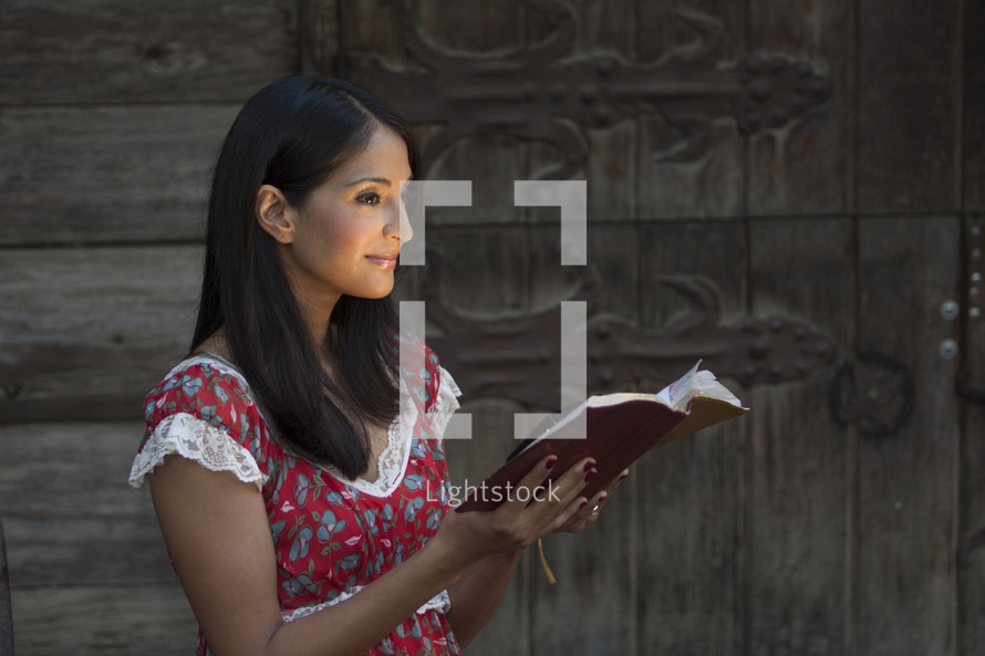 woman standing reading a Bible with her face glowing