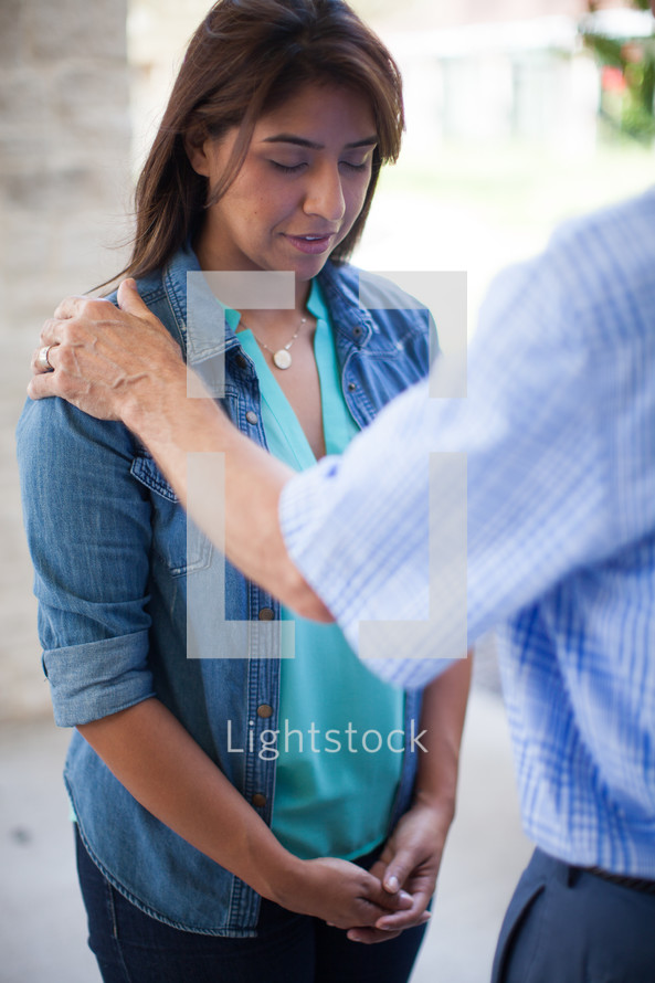 hands on a woman's shoulders in prayer 