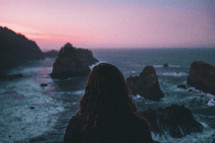 a woman watching the ocean at sunset 