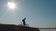 man with a mountain bike standing by a lake shore 