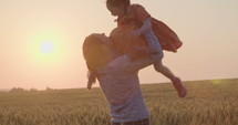 mother and young daughter walking and playing in a field during sunset