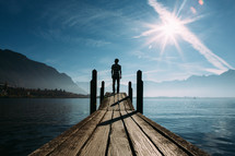 a man standing at the edge of a pier looking out over the water 