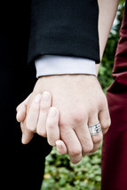 Marriage; couple (man in black suit, woman in red dress) holding hands.
