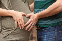mother and father with their hands on mother's pregnant belly