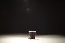 A communion cup filled with wine and a wafer 