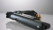 Gun Control. 9mm handgun with bullets rotating on a reflective surface
