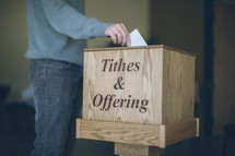 Man putting offering in wooden box.