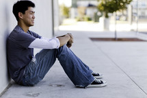 profile of a man sitting on a sidewalk