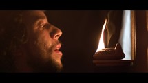 A jewish man blows out the flame on a traditional lamp.