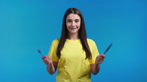Portrait of hungry woman with fork and knife. 